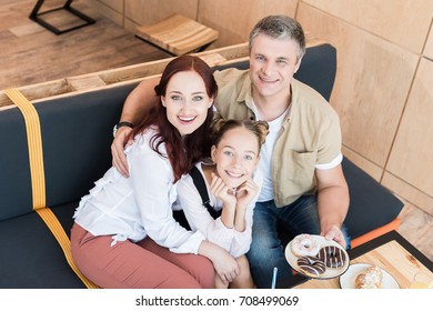 High Angle View Of Beautiful Family With Plate Of Doughnuts In Cafe