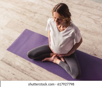 High angle view of beautiful pregnant woman meditating and smiling while doing yoga