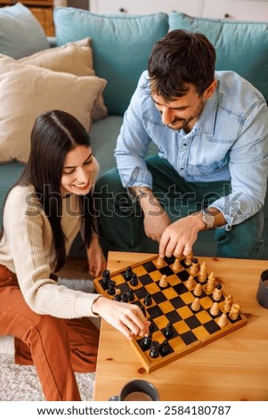 High angle view of beautiful young multi-ethnic couple in love enjoying spending leisure time together at home playing chess and relaxing