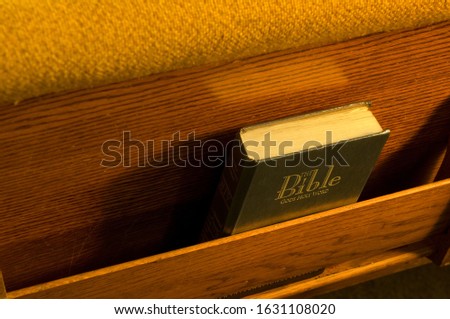 A high angle view of the bible in a small bookshelf behind the chair in the church