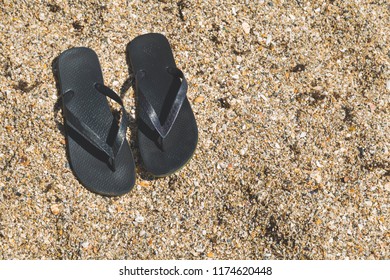 high angle view of black flip flops in beach sand - Powered by Shutterstock