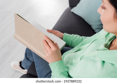 High Angle View Of Blurred Woman Reading Book In Living Room