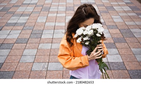 High Angle View Of Brunette Woman Smelling White Flowers Outside