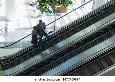 High Angle View Of Business People Interacting With Each Other While Moving Upstairs On Escalator In Office. Modern Corporate Start Up New Business Concept With Entrepreneur Working Hard