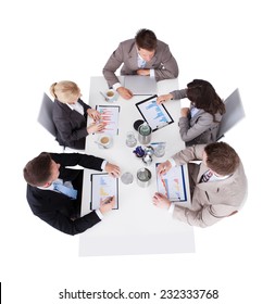 High Angle View Of Business People Discussing Over Financial Graphs At Conference Table Against White Background