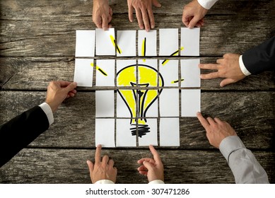 High angle view of businessmen hands touching white papers arranged on a rustic wooden table forming a yellow light bulb. Conceptual for bright business ideas and innovations.  - Shutterstock ID 307471286