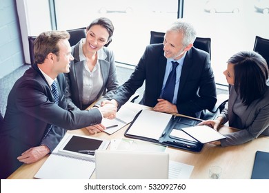 High angle view of businessmen shaking hands in conference room at office