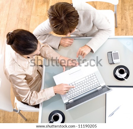 High angle view of businesswomen working together on laptop computer at office.