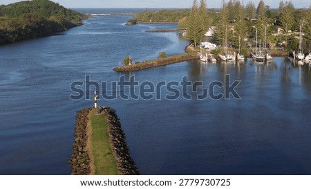 High angle view of a calm river inlet featuring stone breakwalls and moored boats.