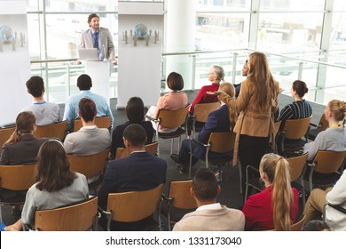 High Angle View Of Caucasian Businesswoman Interacting With Caucasian Businessman Speaking In Front Of Business People Sitting At Business Seminar In Modern Office Building