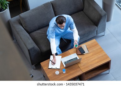 High angle view of Caucasian male doctor writing on clipboard in hospital lobby  - Powered by Shutterstock