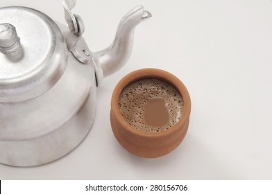 High angle view of chai in traditional cup made of mud with tea kettle isolated over white background
