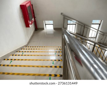High angle view of clean office stairs with yellow and black anti-slip tape and directional arrows for emergency exits.