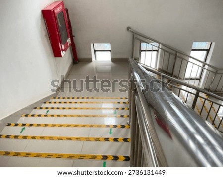 High angle view of clean office stairs with yellow and black anti-slip tape and directional arrows for emergency exits.