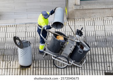 High angle view of a Cleaning worker emptying the trash into his cleaning cart on a city sidewalk