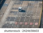 HIGH ANGLE VIEW, CLOSE UP: Motorhome drives trough slow zone at Port of Dover seaport terminal towards ferry dock. Camper with tourist passengers is going to cross the English Channel with ferry boat.