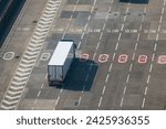 HIGH ANGLE VIEW, CLOSE UP: Container truck moves through slow zone at seaport terminal towards the dock to board a ferry for crossing the English Channel. Busy and organised traffic at Dover harbor.