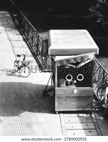 High angle view of a closed retro newsstand kiosk on a sunlit city pavement.