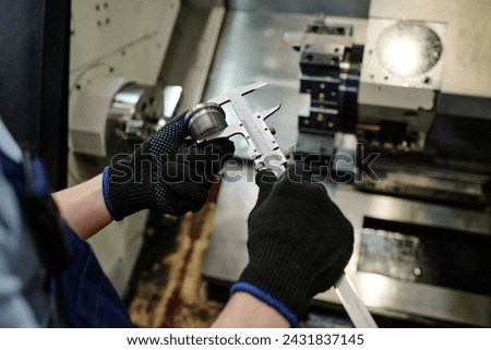 High angle view closeup of hands of unrecognizable turner measuring size of metal part