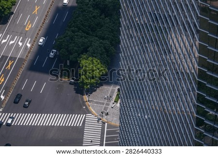A high angle view of a commercial district crossroads with crossings on every arm shows yellow kerb paint tracing the curve of the corner radius. Far above a crowded downtown district.