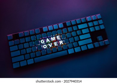 High angle view of computer keyboard with thin frame and backlighted inscription game over. Professional computer game playing, esport business and online world concept.