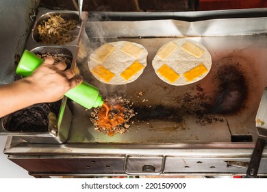 High Angle View Of A Cook Adding Sauce To A Meat On The Grid For Mexican Tacos