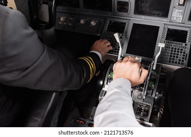 High Angle View Of Co-pilot Using Thrust Lever Near Captain In Airplane Simulator