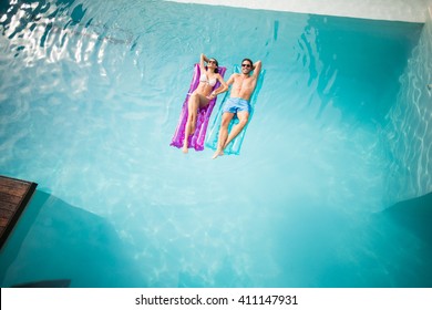 High angle view of couple relaxing on inflatable raft at swimming pool - Powered by Shutterstock