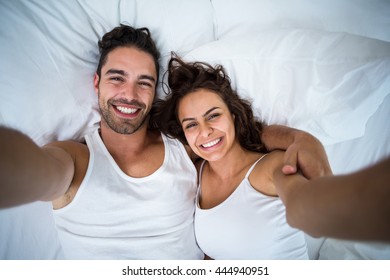 High angle view of couple taking self portrait on bed at home