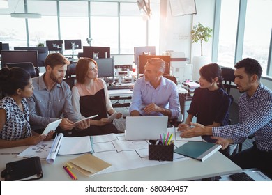 High Angle View Of Creative Business Colleagues Discussing Around Desk In Office