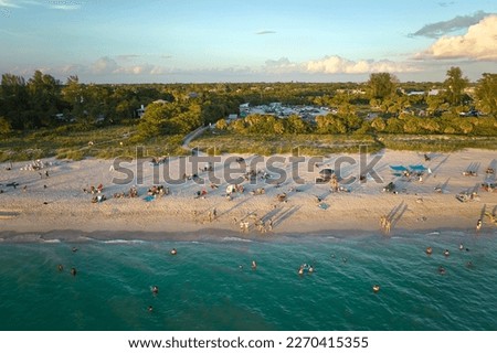 High angle view of crowded Nokomis beach in Sarasota County, USA. Many people enjoing vacations time swimming in ocean water and relaxing on warm Florida sun at sundown