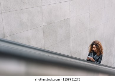 High Angle View Of Curly-haired Black Woman Going Up Escalator