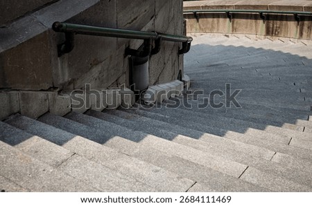 High angle view of curving concrete stairs and metal railings with shadow. 