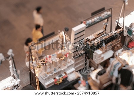 High angle view of customers at indoor festive weekend market. Social pop up event in shopping mall for entrepreneurs and makers. Captured with a tilt-shift lens. Selective focus; bokeh effect.