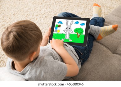 High Angle View Of Cute Little Child Playing Game On Digital Tablet