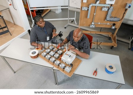 High angle view of deaf man and woman in wheelchair working on electricity equipment in workshop