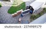 High Angle View Of Delivery Men Unloading The Cardboard Boxes From Truck