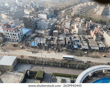 High angle view of a densely packed urban area with residential buildings, roads, construction, and visible rooftops showing a mix of activity and infrastructure