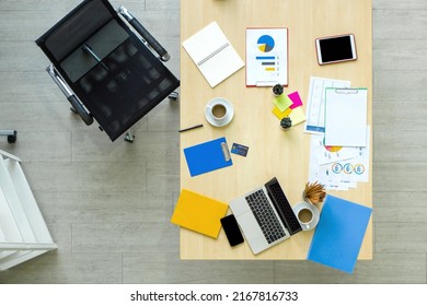 High Angle View Of The Desk In The Office. Laptop Computer, Tablet, Mobile Phone, Credit Card, Coffee, Stationary, Document, Graph, Chart  Are On Wooden Table.