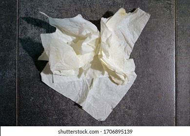High angle view directly from above of a crumpled piece of used kitchen paper towel on a tiled countertop