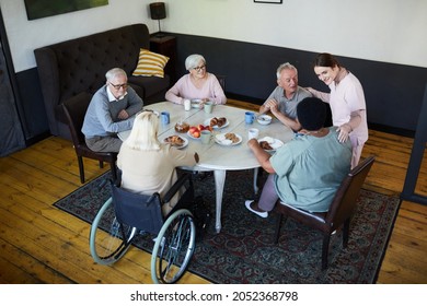 High angle view at diverse group of senior people enjoying breakfast at dining table in nursing home, copy space