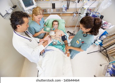 High angle view of doctor and nurses treating critical male patient in hospital - Powered by Shutterstock