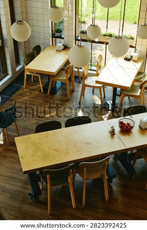 High angle view of empty modern cafe interior with wooden tables and chairs, showcasing contemporary restaurant design for hospitality marketing, vertical