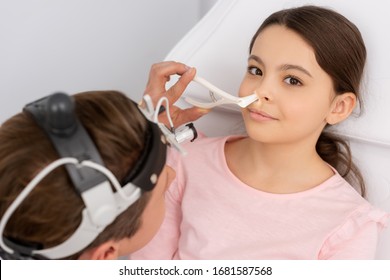 High Angle View Of Ent Physician Examining Nose Of Cute Child With Nasal Speculum