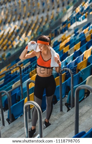 high angle view of exhausted young woman with towel at sports stadium