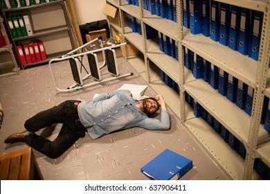 High angle view of fallen businessman and file in storage room at workplace - Powered by Shutterstock