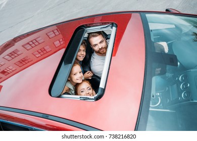 High Angle View Of Family Looking Out Of Sunroof Of Car