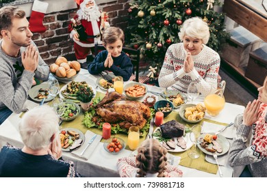 High Angle View Of Family Praying On Christmas Dinner