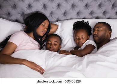 High angle view of family sleeping together on bed at home