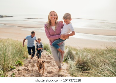 High Angle View Of Family Walking Up A Sand Dune At The Beach.